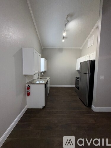 A kitchen with white cabinets and a black refrigerator.