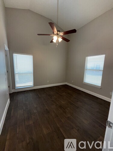 A room with a ceiling fan and wood flooring.