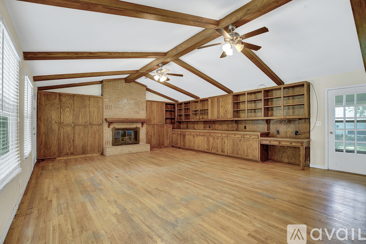 A spacious room with wooden floors and a fireplace.