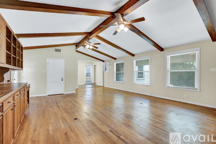 A spacious room with wooden floors and a ceiling fan.