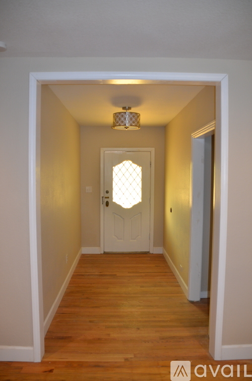 A hallway with a white door and wooden floor.