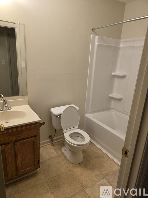 A white toilet sits in a bathroom next to a sink and a walk-in shower.