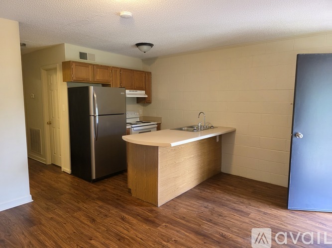 A kitchen with a refrigerator, sink, and wooden cabinets.
