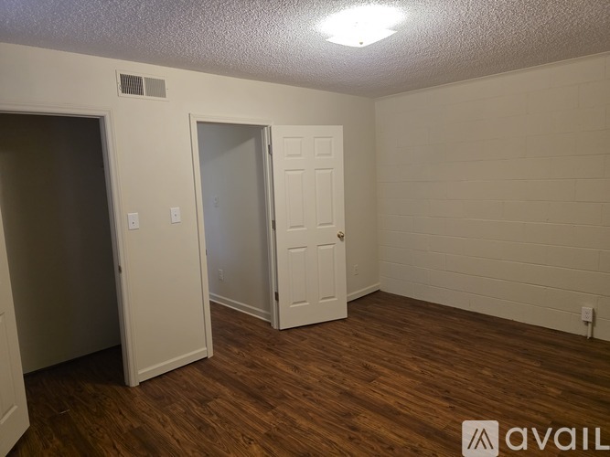 A room with wood flooring and two doors, one of which is open.