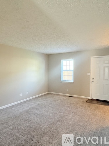 A room with a carpeted floor, a door, and a window.