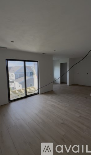 A room with wooden flooring and a large window overlooking a house.
