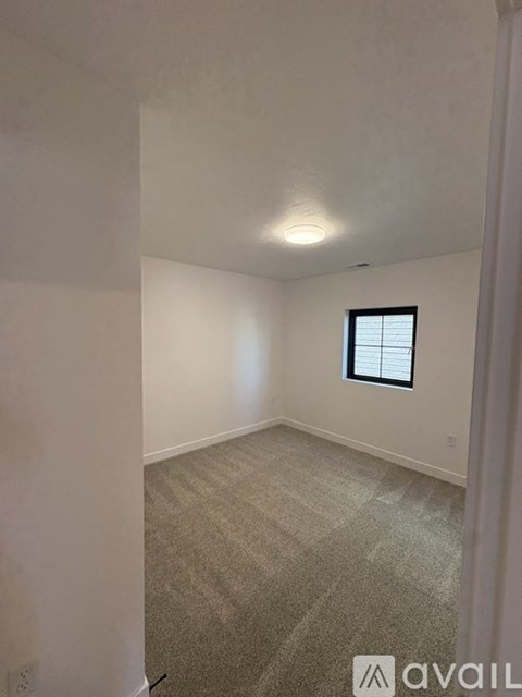 A room with a wooden floor and white walls with a door open to another room.