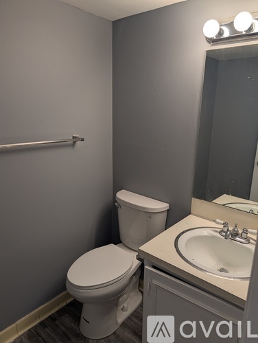 A bathroom with a toilet, sink and mirror.