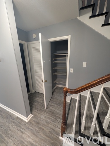 A staircase with a wooden handrail and a white wall with a doorway leading to a closet.