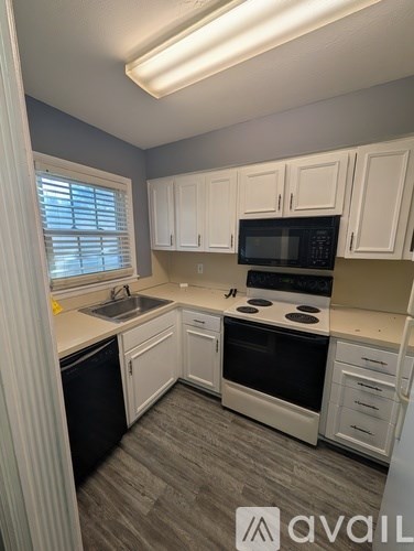 A kitchen with white cabinets and a black microwave.