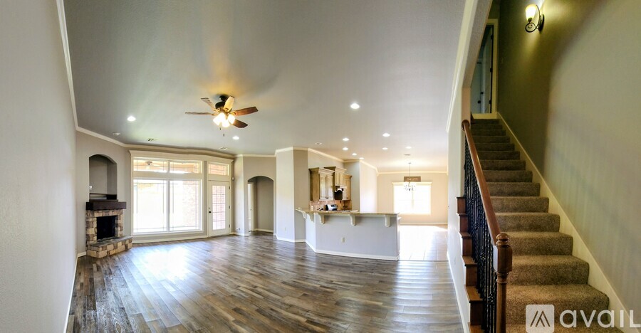 A spacious living room with hardwood floors and a staircase leading to the upper level.