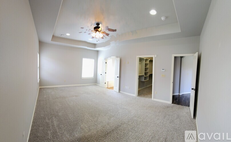 A spacious room with a carpeted floor and a ceiling fan.