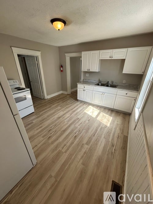 A kitchen with wooden floors and white appliances.