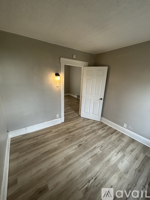 A room with wooden flooring and a white door.