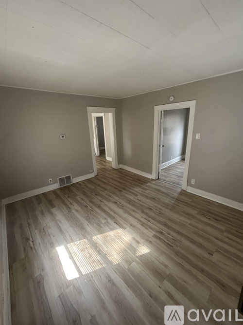 A room with wooden flooring and two doors.