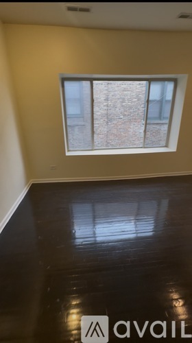 A room with a window and wooden flooring.