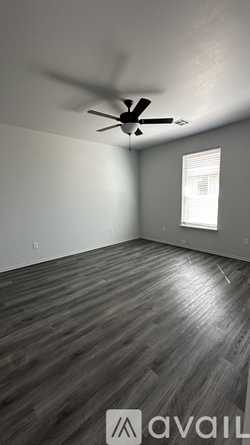 A room with a ceiling fan and wooden flooring.