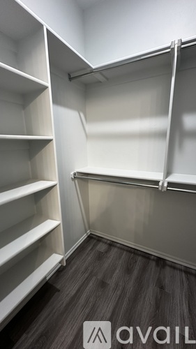 A walk-in closet with white shelves and a grey floor.