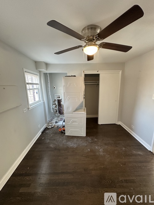A room with a ceiling fan and wooden flooring.