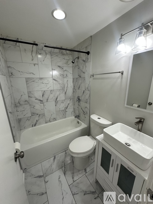 A bathroom with a marble tile wall and a white bathtub.