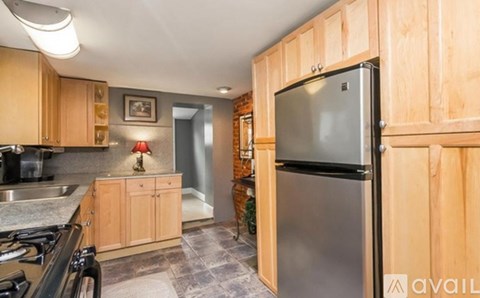 A kitchen with wooden cabinets and a stainless steel refrigerator.