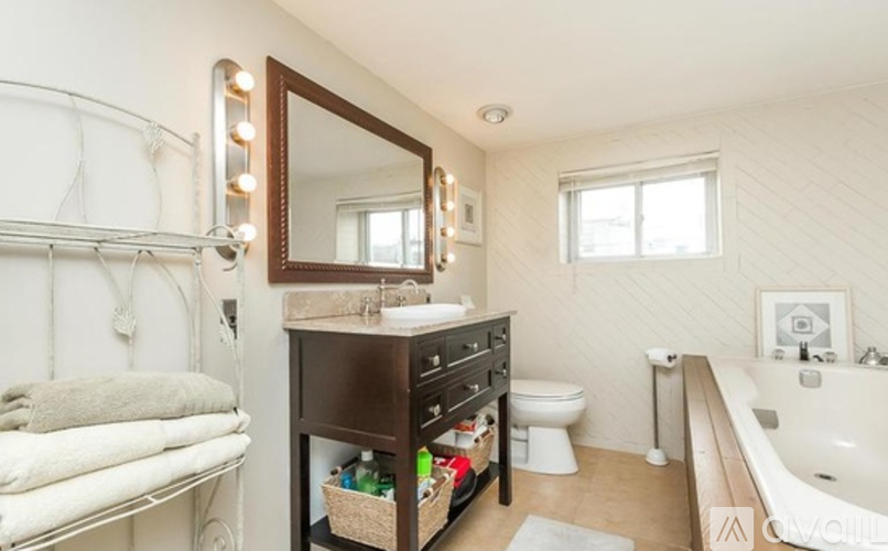 A bathroom with a white tub, a white toilet, a white sink, a white towel, and a white wall.