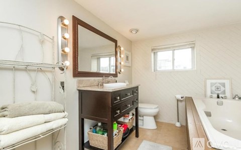 A bathroom with a white tub, a white toilet, a white sink, a white towel, and a white wall.