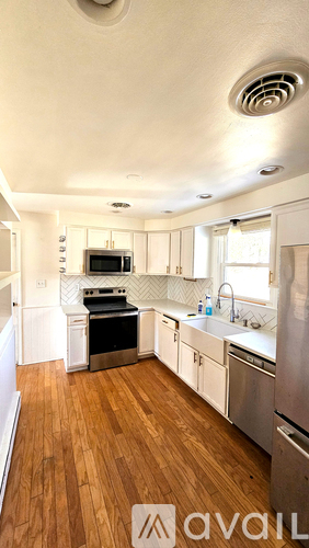 A kitchen with white cabinets and a wooden floor.
