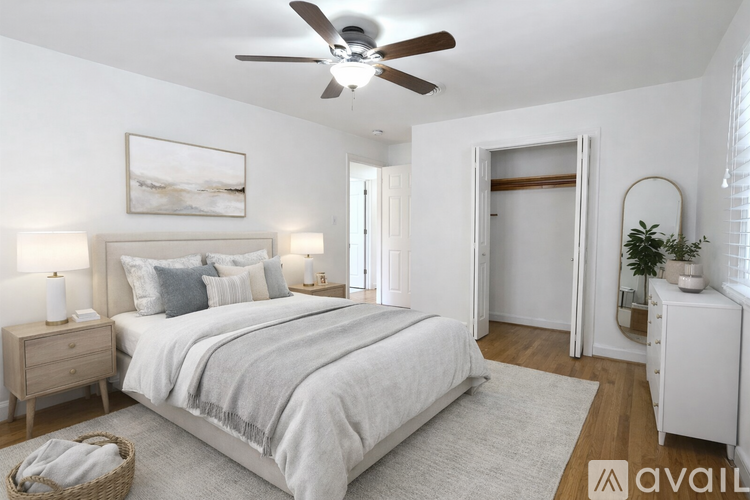 A bedroom with a large bed, a ceiling fan, and a nightstand with a lamp.