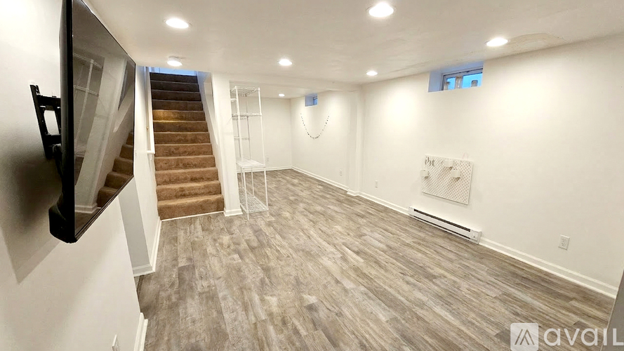 A spacious room with a staircase and a painting on the wall.