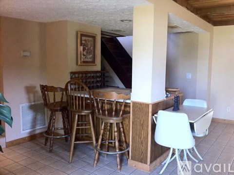 A dining room with a table surrounded by chairs.