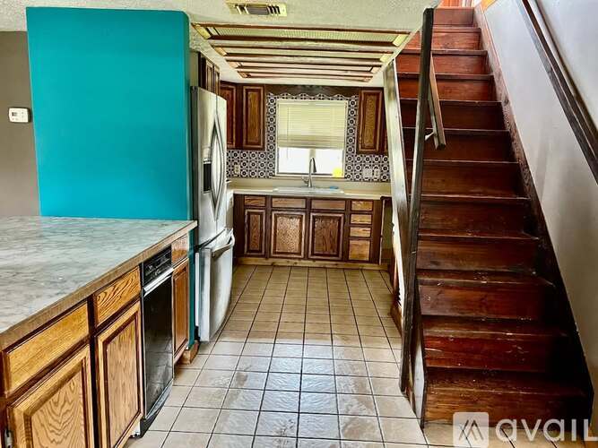 A kitchen with a staircase leading to the upper floor.