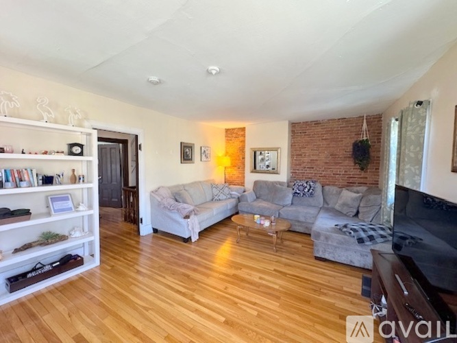A living room with a grey couch and a wooden floor.