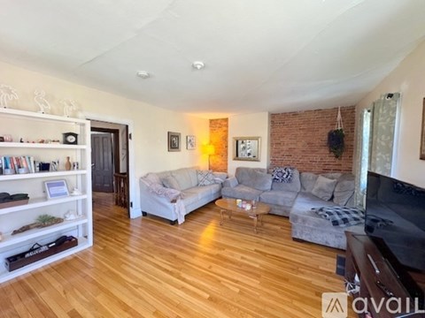 A living room with a grey couch and a wooden floor.
