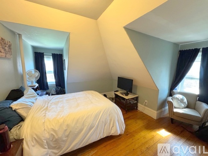 A bedroom with a large bed and a chair.