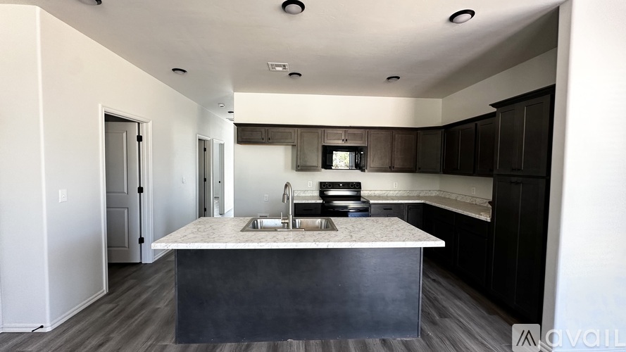 A modern kitchen with a marble countertop and dark wood cabinets.