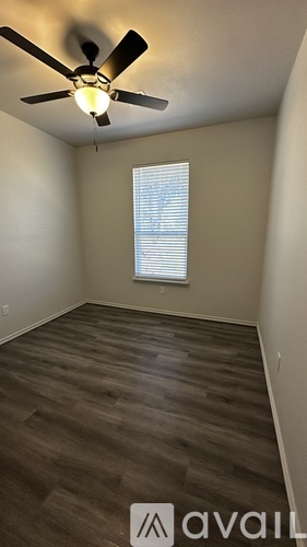 A room with a ceiling fan and a window with blinds.