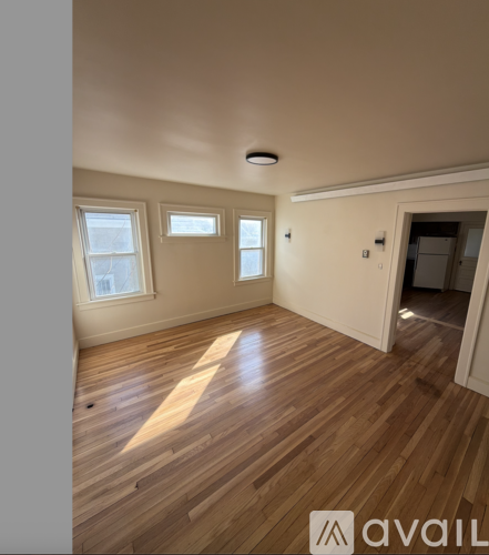 A room with wooden flooring and three windows.