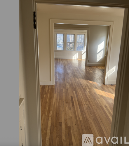A hallway with wooden floors and a doorway leading to another room.