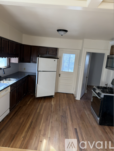 A kitchen with wooden floors and white appliances.