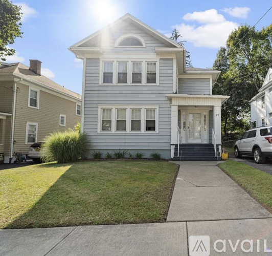 A two-story house with a front porch and a car parked in the driveway.