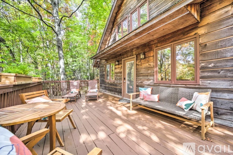 A wooden deck with a table and chairs is surrounded by trees.