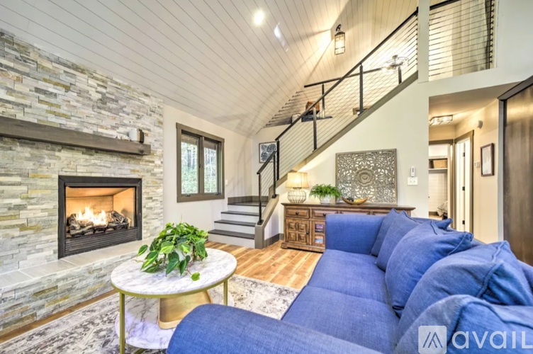 A living room with a stone fireplace and a blue couch.
