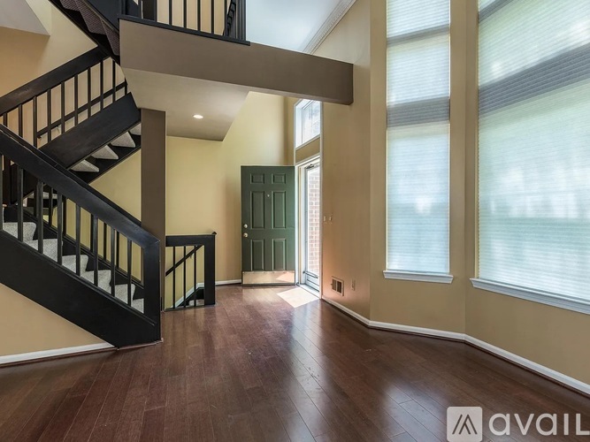 A spacious room with a staircase and a green door.
