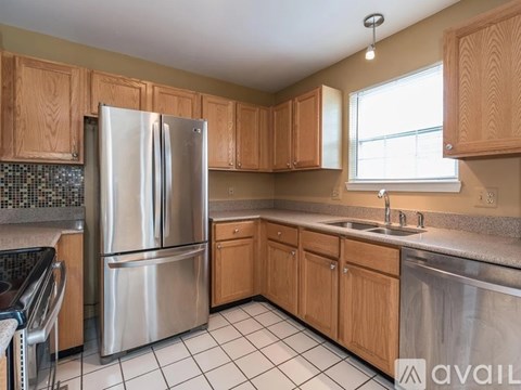 A kitchen with a stainless steel refrigerator and wooden cabinets.