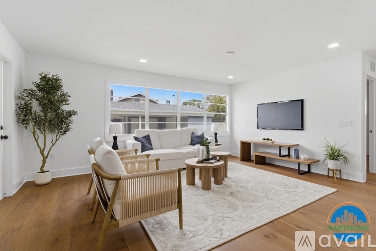 A living room with a white couch, a wooden chair, a small table, and a television.