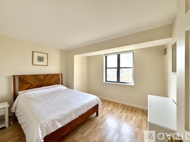 A bedroom with a bed, nightstand, and window.