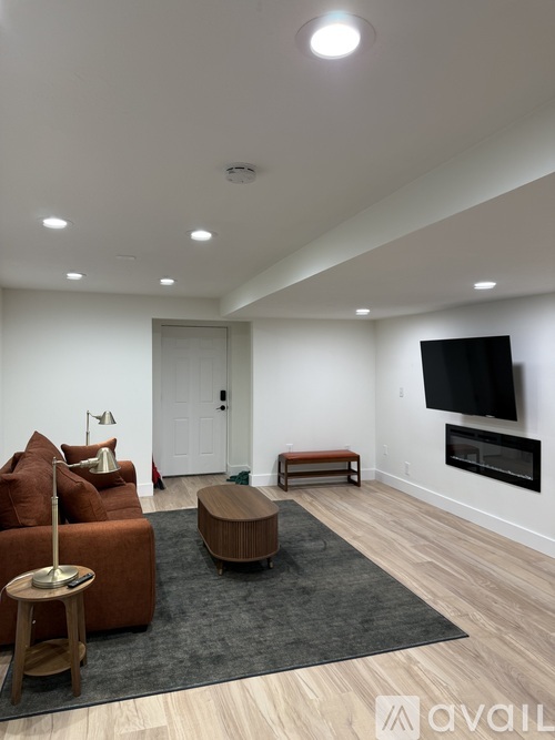A living room with a brown couch, a wooden table, and a flat screen TV mounted on the wall.