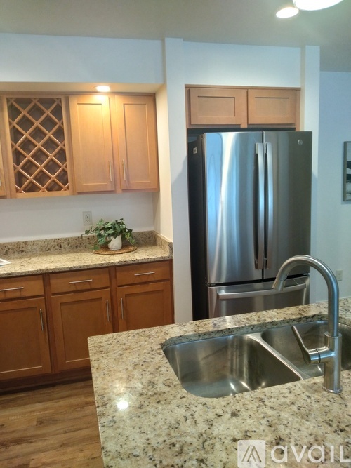 A kitchen with a granite countertop and a stainless steel refrigerator.