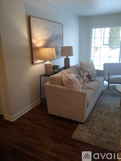 A living room with a couch, a table with a lamp, and a painting on the wall.